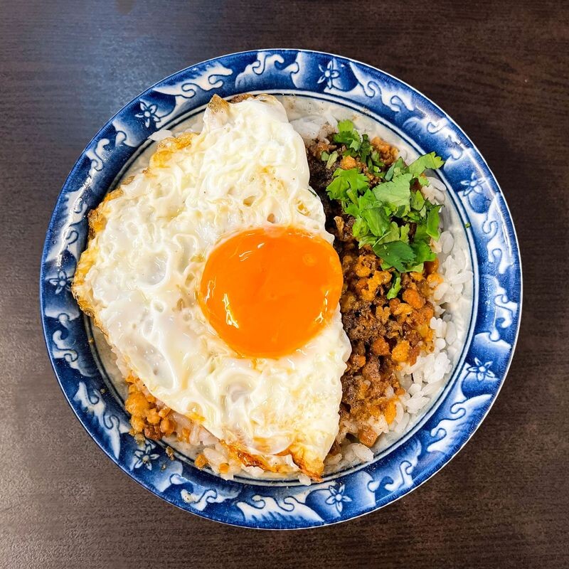 「秀明豬心冬粉」的「月見肉燥飯」很受歡迎，肉燥純以瘦肉熬煮，有別於其他作法，配上油亮的半熟煎蛋，絲滑的蛋液混合鹹香米飯，令人回味無窮。（Michelin提供）