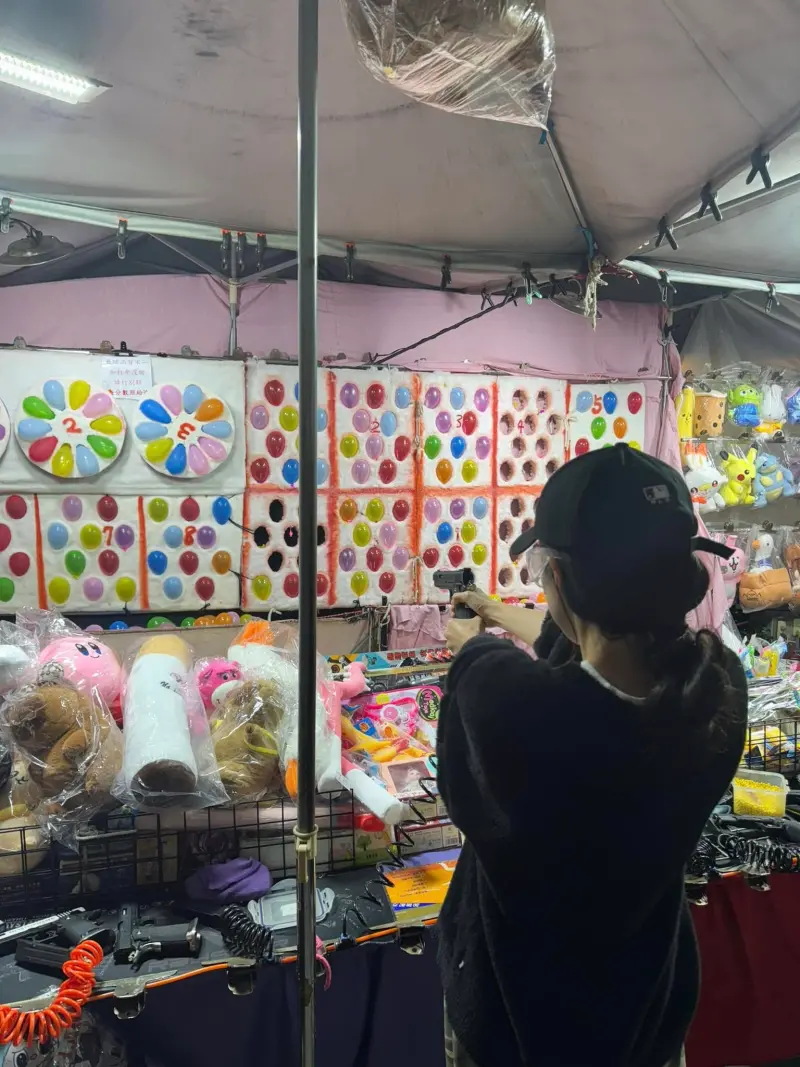 ▲李多慧在夜市玩射氣球,姿勢看起來有模有樣。(圖/李多慧臉書)