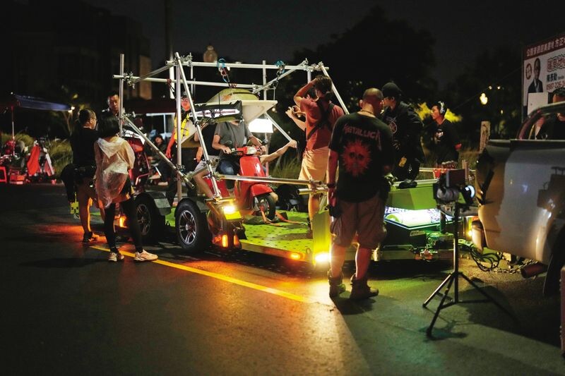 傅孟柏、柯佳嬿(上圖)扛浴缸騎機車的荒誕戲碼,拍攝過程出動大型拖板車,並利用鋼絲吊掛完成(下圖)。(Netflix提供)
