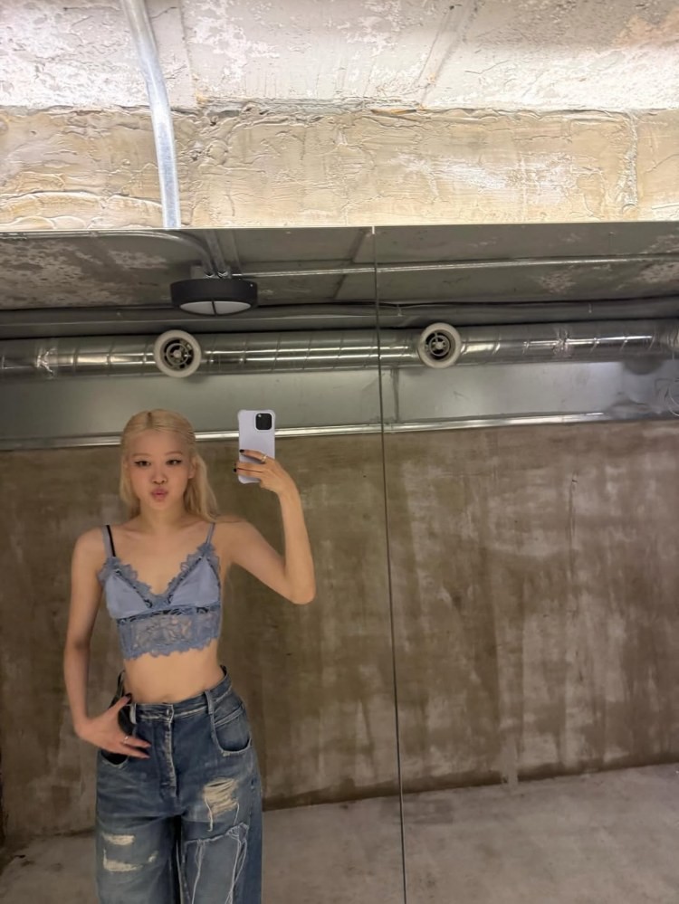 Rosé身穿藍紫色細肩蕾絲短上衣,搭配破壞感牛仔寬褲,在鏡子前自拍,盡顯優雅風範。