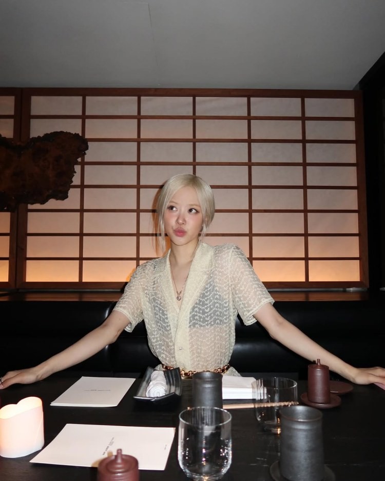 Rosé身穿奶油色蕾絲洋裝,坐在餐廳座位上,展現低調卻難以忽視的優雅氣場。