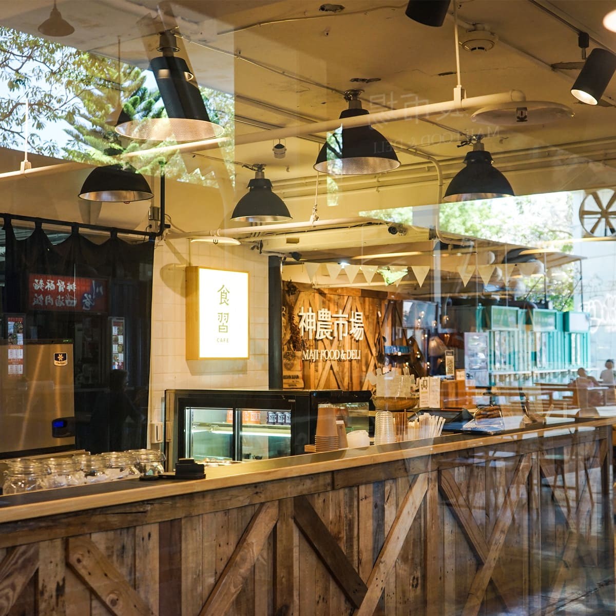 隱身在 MAJI 集食行樂市集裡的「食習 cafe」，結合神農生活一直以來傳遞的輕鬆自在生活概念，木質櫃檯與開放式座位讓人有種在路邊小憩的隨性感。