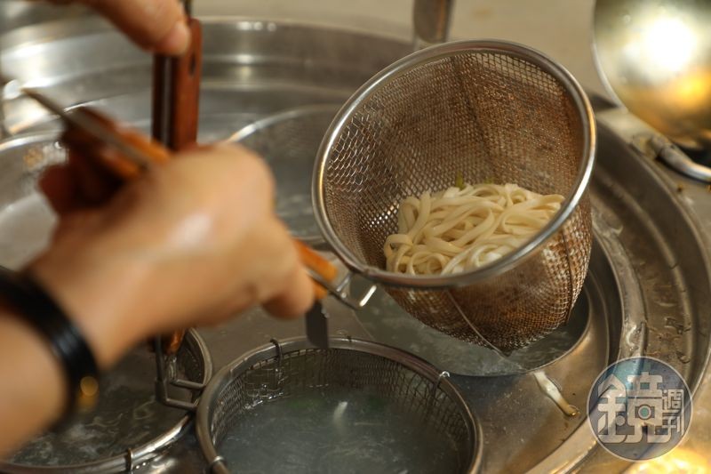 老闆熟練地拉起漏勺,開始把煮熟的麵「切切切」地涮甩去水分。