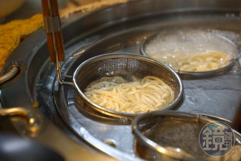麵條在漏勺中翻滾,冒著熱氣。