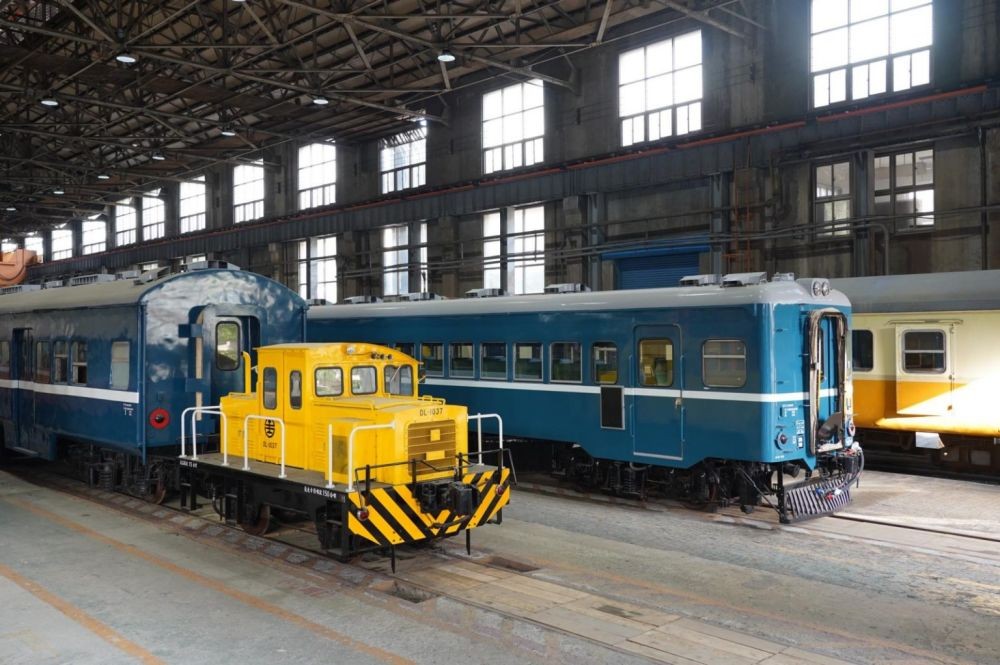「組立工場」的背景,它啟用於 1935 年,為台北機廠最具代表性的核心建築物,這個工場的特色是採用大跨距、無內柱設計,以容納鐵道車輛維修所需的空間,展現了當時的工業建築規模。