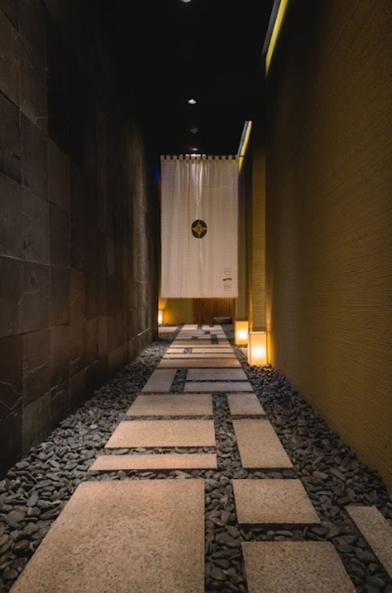走過一段石板路，穿過印有押野家徽的暖簾，才正式進入用餐空間。（赫士盟提供）