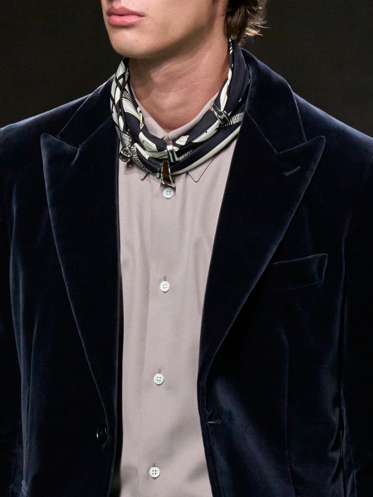 愛馬仕2025秋冬男裝秀亮點：絲巾是 Hermès DNA 中無法被忽略的單品，在本季秋冬男裝秀裡依舊成為最穩定卻又畫龍點睛的配件，這次不僅細緻滾邊、印花邊框等變化多端，打法是自己DIY把戒指穿過，再繞頸後作為裝飾，俐落有型又溫柔。