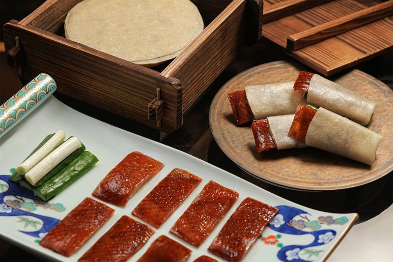 片好的鴨皮,以手工桿製的小麥餅皮包裹,搭配宜蘭三星蔥段、小黃瓜與特製甜麵醬。(北投晶泉丰旅提供)