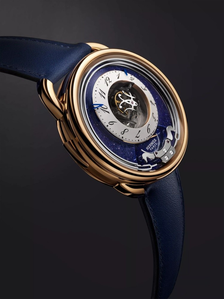 Hermès 愛馬仕 Arceau Duc Attelé 陀飛輪三問腕錶,將高級製錶工藝與馬術精神結合,呈現中央「三軸陀飛輪」與「三問報時」兩大複雜功能之美。錶盤上打造成駿馬形象的音錘;透過音錘擊打細長音叉形的淬火鋼音簧,進行時、刻、分報時,發出如教堂鐘聲般的樂音。