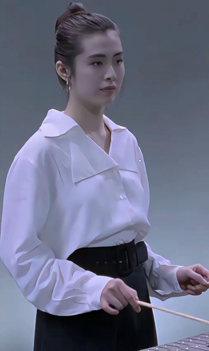 白襯衫與高腰黑裙,向來是歷久不衰的經典組合,而王祖賢的詮釋關鍵在於「結構感」。她選擇略為寬鬆的大翻領襯衫,刻意放大的領片為上半身建立清楚輪廓,也自然拉長頸部線條;下身則搭配腰線明確的高腰西裝裙,並以同色寬版腰帶強調比例,使整體身形看起來更加修長而穩定。襯衫紮入裙頭,卻保留布料的自然鬆度,讓正式單品不顯拘謹,反而多了一份從容與氣場。這種以剪裁取勝、以比例說話的穿法,即使是30多年後的今日,依然是極具說服力的都會穿搭範本。