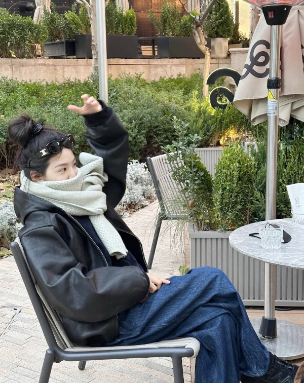 我一直覺得,章若楠的私服最迷人之處,不在於堆疊了多少當季爆款,而是在於那股恰到好處的鬆弛感。看看這張在露天咖啡座的穿搭照,她選擇了一件極具存在感的寬廓形皮外套,那種皮革特有的冷冽光澤,被頸間厚實的淺灰織紋圍巾完美中和了,剛柔並濟。最讓人有感的便是那高高紮起的丸子頭,以及隨手推在髮際線上的墨鏡。這樣看似隨意的小動作,卻能在厚重的層次穿搭中,更加透出一種「Well〜我只是隨便穿穿」的美式輕鬆感。不妨多加參考吧。