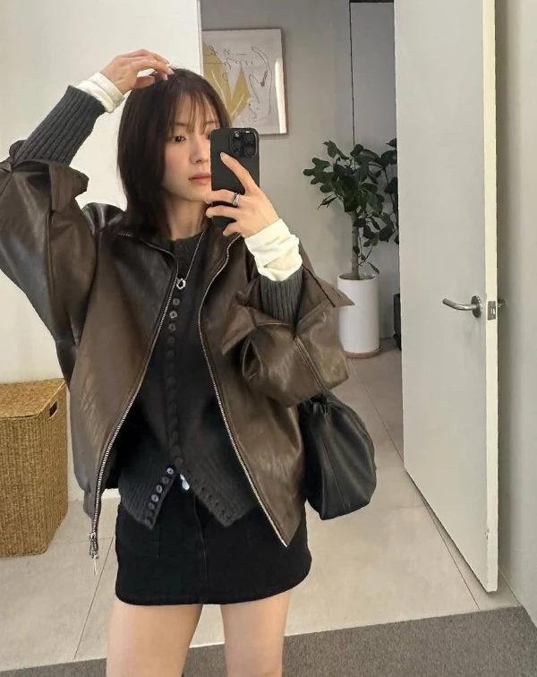 李世榮用一件復古感的咖啡色皮外套作為主角,內搭黑色排釦上衣與短裙,打造出俐落又顯腿長的全黑基底,再透過袖口微微露出的白色內搭增加層次亮點,讓整體不會過於沉重。皮革的率性感中和了短裙的甜美,搭配隨性手拎的黑色包款,多了一點不經意的時髦感,看起來就像隨手一拍都很有態度。