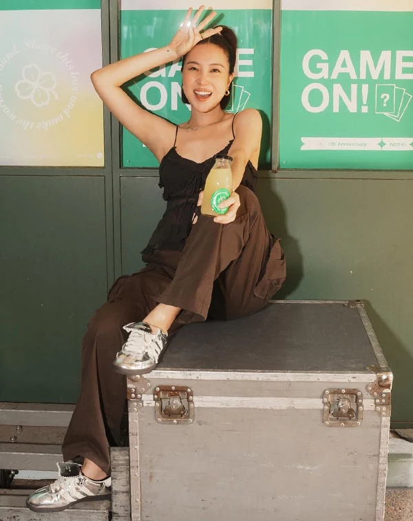 不藏私！Melinda的這套絕對值得我們偷師！看似隨性地坐在箱子上，實則暗藏許多顯瘦又高級的搭配心機。Melinda以一件細肩帶黑色上衣搭配同色系寬褲，展現不費力的慵懶女人味。這種穿搭不只能視覺拉長比例，利用不同材質（像是柔美的雪紡上衣與硬挺的口袋工裝寬褲）更能營造層次、打破單調感。