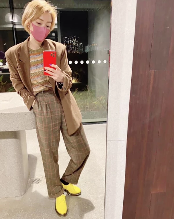 這套穿搭,我覺得完全展現了鄭秀文對復古玩味的高階減齡技巧。整體色調,以溫暖、低調的棕色系為基底,卻用一雙亮黃色短靴瞬間抓住視線,這種衝突感配色不僅讓造型更有活力,也巧妙地轉移了對年齡的關注,成功打造年輕又叛逆的感覺。復古元素的疊加,則是另一個亮點,格紋西裝套裝,配上條紋細節,將傳統復古單品玩出新意,不顯沉悶。