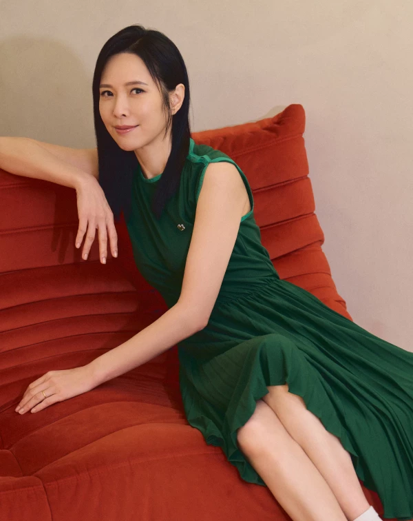 許多熟齡女性容易自限於黑白灰,天心這身復古飽和的「極致墨綠」洋裝直接給了我們新靈感。這類飽和色不僅具有極佳的顯白、提亮氣色效果,縮腰的傘擺剪裁更能自然勾勒出腰身。我們日常在穿這類優雅洋裝時,減齡的絕招就在腳上——千萬別配端莊的高跟鞋,那會顯得老氣沉重;像天心一樣混搭一雙復古的白色運動短襪與休閒鞋,利用這種微小的運動風反差,就能把及膝洋裝穿得像女大生一樣充滿活潑朝氣。