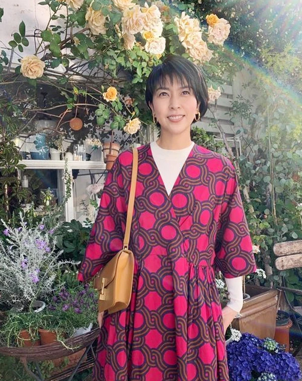 松隆子的這套，其實很容易讓人多看幾眼。桃紅色幾何印花洋裝，本身已經很有存在感，但她在裡面多搭了一件白色高領針織後，整體感覺，就立刻變得柔和很多，也讓亮色不會顯得太過強勢。再加上焦糖色皮革肩背包和簡單的金色耳環，整體配色看起來很有春夏感，帶點成熟感之餘，又不會顯老。