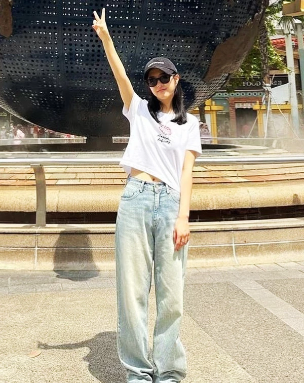 這套穿搭簡直是「美式復古少女」的完美範本，活力感都要溢出螢幕了！朴寶英聰明地用了小隻女必學的「上短、下長」黃金公式，短版白T輕微露出一截腰部肌膚，不僅顯得俏皮，更讓視覺腰線往上拉。下半身搭配刷色寬版牛仔褲，營造出一種「天生長腿」的鬆弛感。最後再戴上一頂黑色棒球帽和墨鏡，讓整個人看起來就像是剛從加州校園走出來的大學生，不僅減齡滿分，更把158公分的嬌小身材穿出了178公分的潮酷氣場，小隻女們對要直接複製貼上！
