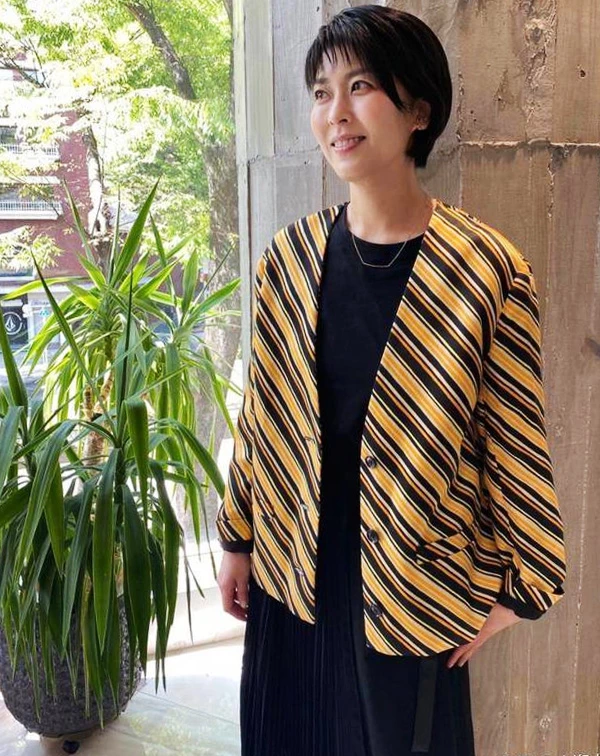 松隆子這次則改用全黑內搭當基底，原本比較容易顯得沉悶，但外面多罩了一件黃、黑斜條紋短版外套後，整個人立刻有精神很多。尤其，斜條紋本來就比橫條紋更有延伸感，看起來也會比較修飾身形，再上短版和七分袖的設計，視覺上也讓比例變得更輕盈。配件部分，她也沒有搭太多，只用一條簡單的金屬短鍊點綴，反而讓整體看起來乾淨又有重點。這樣的穿法，其實很適合平常喜歡黑色系的人，不會太單調，又能保留一點俐落感。