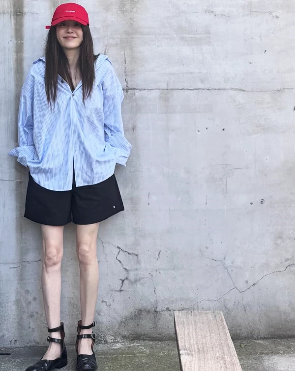 這套造型，完美演繹了「夏天如何利用高彩度配件，點亮穿搭」，高賢廷以淺藍色條紋襯衫，搭配黑色短褲，清爽色調瞬間降溫。不過最精彩的減齡穿搭重點，莫過於那頂亮眼的紅色棒球帽，與腳下的繫帶瑪莉珍鞋。紅色帽子，不僅能增添年輕活力，更為簡約襯衫注入街頭感；而復古瑪莉珍鞋與短褲的組合，則巧妙地拉長腿部比例，散發出如大學生般的俏皮感。