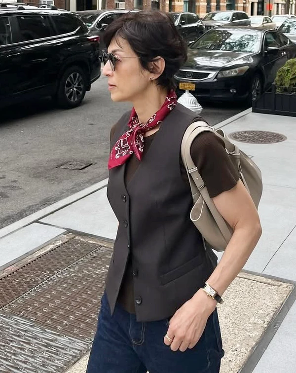 在紐約街頭，鈴木保奈美以深咖啡色西裝背心內搭同色系短袖上衣，下身搭配休閒牛仔褲，最亮眼的，絕對是頸間那條復古絲巾。當我們穿著大範圍的深色、大地色系或基本款正裝時，秘訣就在於加入高對比的配件。學她在領口繫上一條鮮豔的印花小方巾，並配上一副百搭的黑色墨鏡，不僅能一秒聚焦視覺、修飾頸部線條，更能為沉穩的穿搭注入滿滿的美式復古活力。