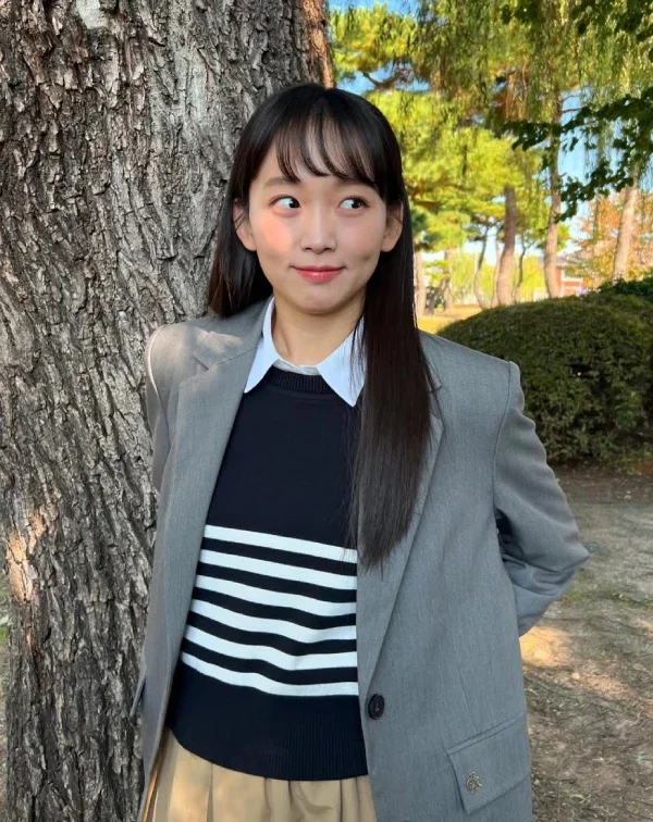 許多人擔心灰色西裝外套會顯老,但秦基周卻在裡面內搭了一件條紋針織衫及白色襯衫,直接打破西裝的沉悶感,下半身配上卡其色裙裝,完美平衡了正式與休閒,不僅是高級的微甜職場穿搭,還能給人一種專業度不減,且充滿朝氣的時髦印象。