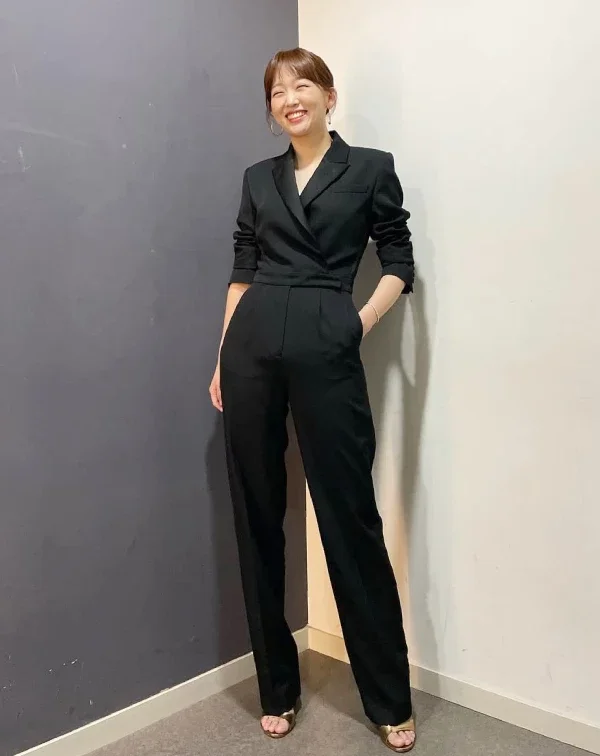 秦基周也能展現出截然不同的減齡風格。她穿著全黑的西裝套裝,但褲子是寬鬆的寬褲版型,打破了傳統西裝的沉悶感。想要將西裝穿出年輕感,重點在於「放鬆」。選擇版型偏大或寬褲造型的西裝,並搭配休閒的鞋款(如涼鞋、運動鞋),就能平衡西裝的正式感,展現出自信大氣的都會女性魅力。