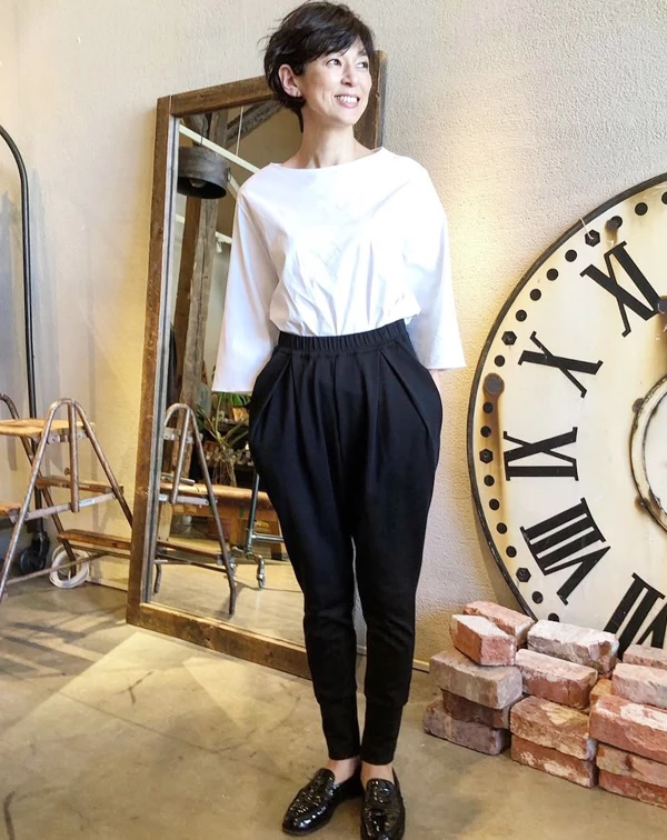 鈴木保奈美僅用最經典的黑白配，就穿出強烈的時髦感。她選擇一件帶有立體剪裁、一字領的七分袖白上衣，下半身搭配高腰且大腿廓形寬鬆、小腿收緊的黑色飛鼠褲。一般人穿黑白配最怕流於呆板的上班族制服，秘訣就在於「打破常規的剪裁」。