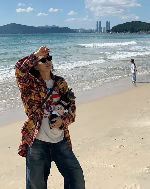 覺得單穿亮色T恤不自在？不如就學學金瑞亨的搭法，外搭一件格紋襯衫當薄外套，整體造型層次分明，既有美式復古的街頭感，又兼具防曬、修飾手臂的效果，完美融入了海邊輕鬆、自在的度假氛圍。