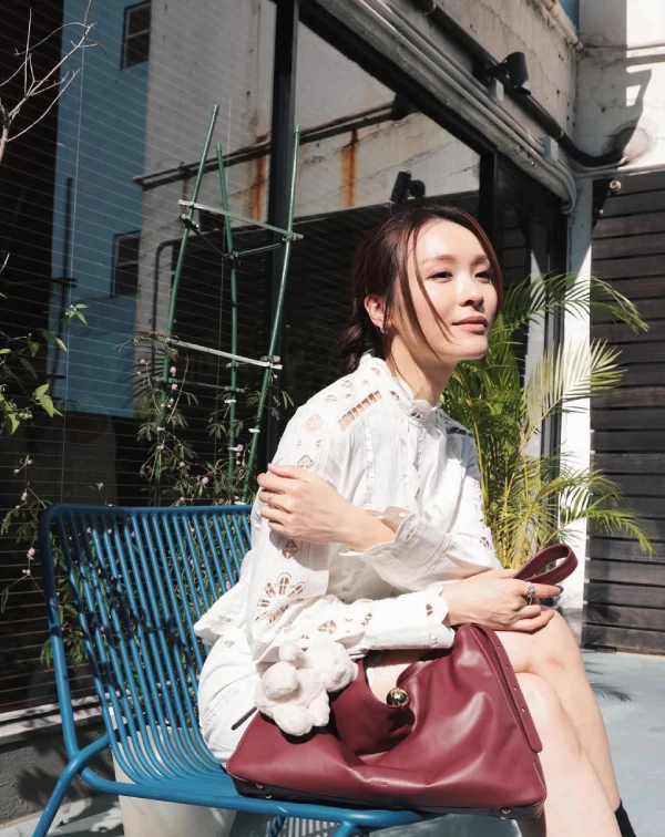 在照片中,李佳芯完美示範了什麼叫「不費力的初夏逆齡感」!很多同齡女性擔心蕾絲會穿得像桌布,那是因為版型沒選對。首先,挑選一件帶有精緻幾何鏤空剪裁的白色蕾絲襯衫洋裝,領口帶點小立領設計,能順便修飾頸部線條;第二步,將頭髮溫柔地低紮成雙辮或低馬尾,這樣能瞬間打破蕾絲的貴氣,多一分鄰家氣息,讓整個人散發出有如在午後巴黎街頭喝咖啡的鬆弛感。