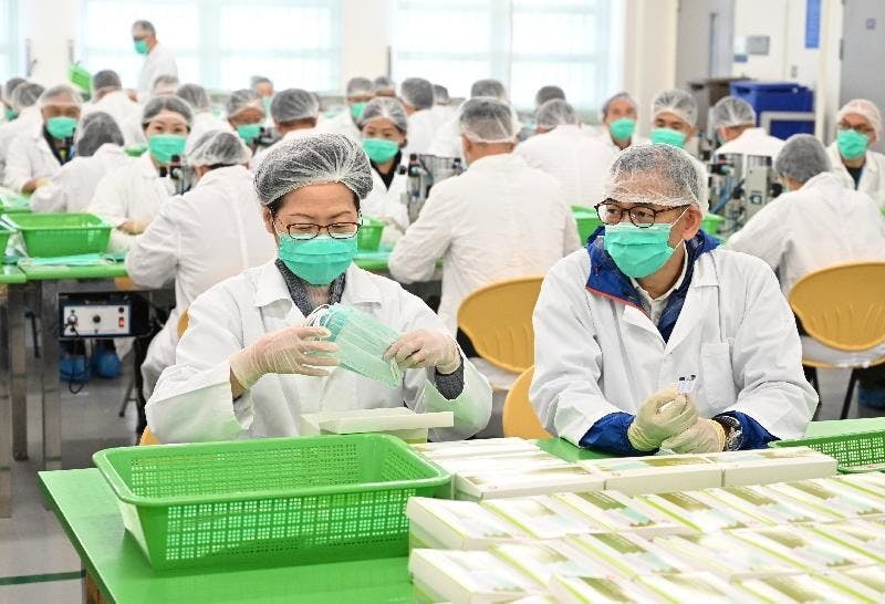 行政長官林鄭月娥3月15日到訪懲教署羅湖懲教所。圖為林鄭月娥（左）參與包裝口罩的工作。旁為懲教署署長胡英明。（政府新聞處）