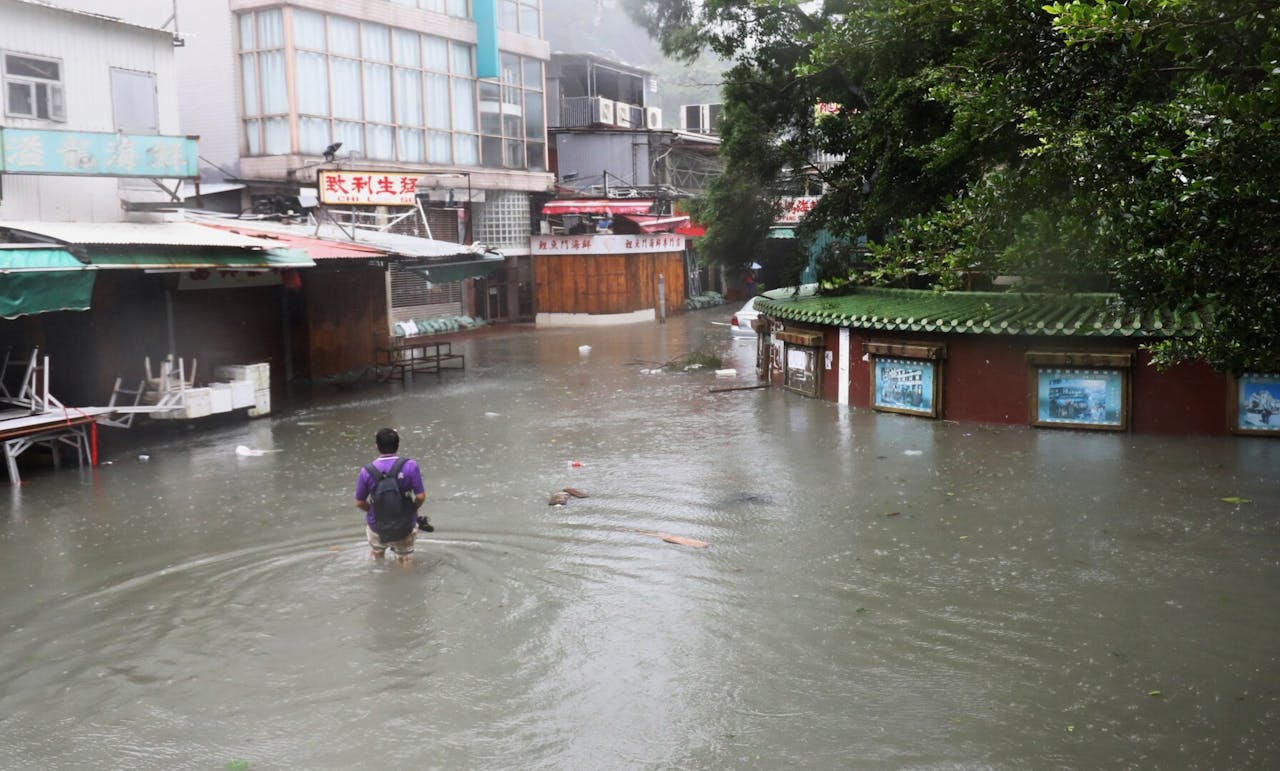 在大風大雨下走過水深過膝的街道，實在舉步維艱。（亞新社）