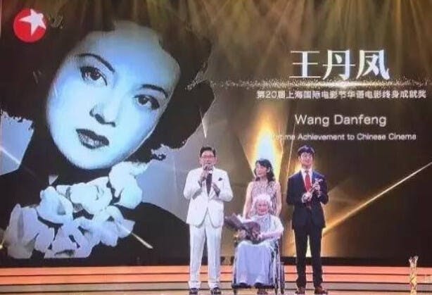 第20屆上海國際電影節（2017）舞台屏幕：王丹鳳，左為王丹鳳年輕時照片。舞台中心坐輪椅的王丹鳳領取「華語電影終身成就獎」。（上海網絡圖片）