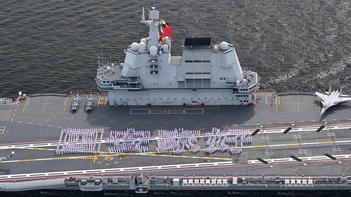 700餘名山東艦官兵在甲板排出「國安家好」字樣，與岸邊熱情揮舞國旗區旗的香港市民形成歷史性同框。（香港政府新聞網）