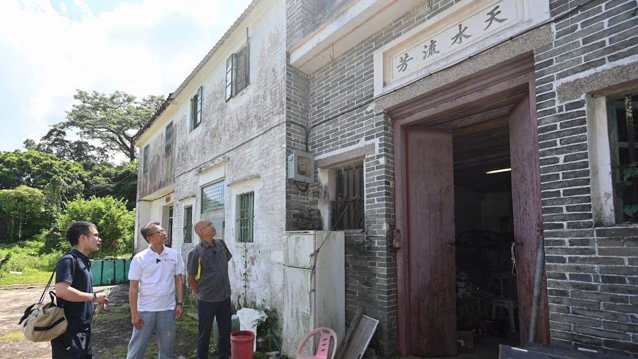陳茂波（左二）與同事到抗戰遺址西貢大屋，大門上方匾額題有「天水流芳」四字。（財政司司長辦公室）