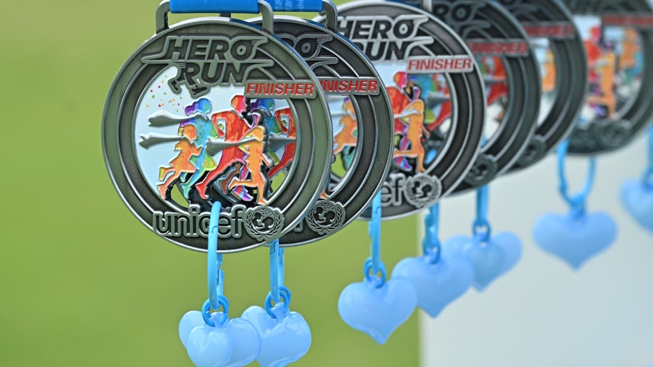 「HERO RUN — 童您跑」3公里障礙賽獎牌上的兩顆藍色心心吊飾，寄託參賽家庭對大埔災後社群的真摯祝福。（作者提供）