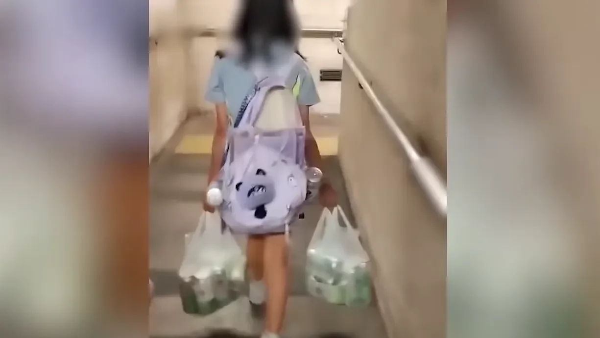 女孩背着破爛書包、拖着沉重物品、步伐緩慢,這些都是沉默的訊號。(網絡影片截圖)