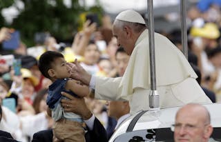 Pope Francis blesses a child as he arrives for a closing Holy Mass of the 6th Asian Youth Day in Haemi Castle in Haemi