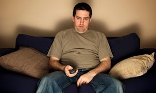 Bored,_overweight_man_sits_on_the_sofa