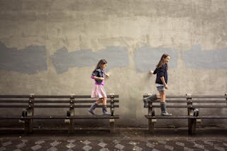 Two girls (8-15) walking on benches