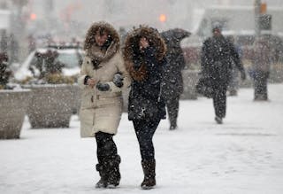 People walk through heavy falling snow in Times Square in New York