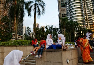 Women talk in front of the Petronas towers in Kuala Lumpur