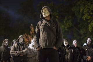 Protesters wearing Guy Fawkes masks stand in a park in downtown Belgrade