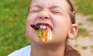 The child is eating jelly candy worms.