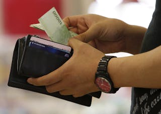 A customer takes money out of his wallet at a supermarket counter in Seoul