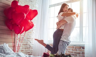Beautiful young couple at home. Hugging, kissing and enjoying spending time together while celebrating Saint Valentine's Day wit