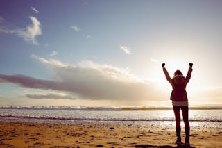 舉手＿自由＿Rear view of woman looking at the sea with hands up on the beach