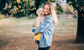 Pregnant woman carrying dog in park