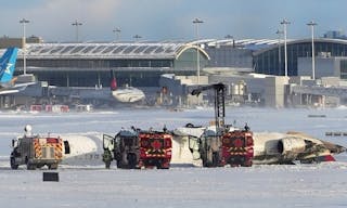 An aircraft from Delta Airlines sits upside down on the tarmac at Toronto Pearson International airport