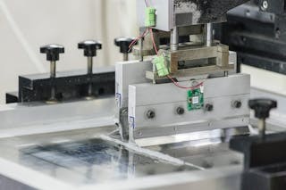 智慧貼紙執行長張焜傑正專注觀察電路板的錫膏印刷製程。印刷機台的刮刀上方已安裝智慧貼紙研發的感測器,用來即時監測運作時的振動數據,確保印刷精度。