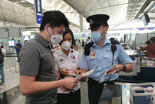 警方聯同入境處人員到香港國際機場，派發宣傳單張提醒遊客不要上當。（政府新聞處圖片）